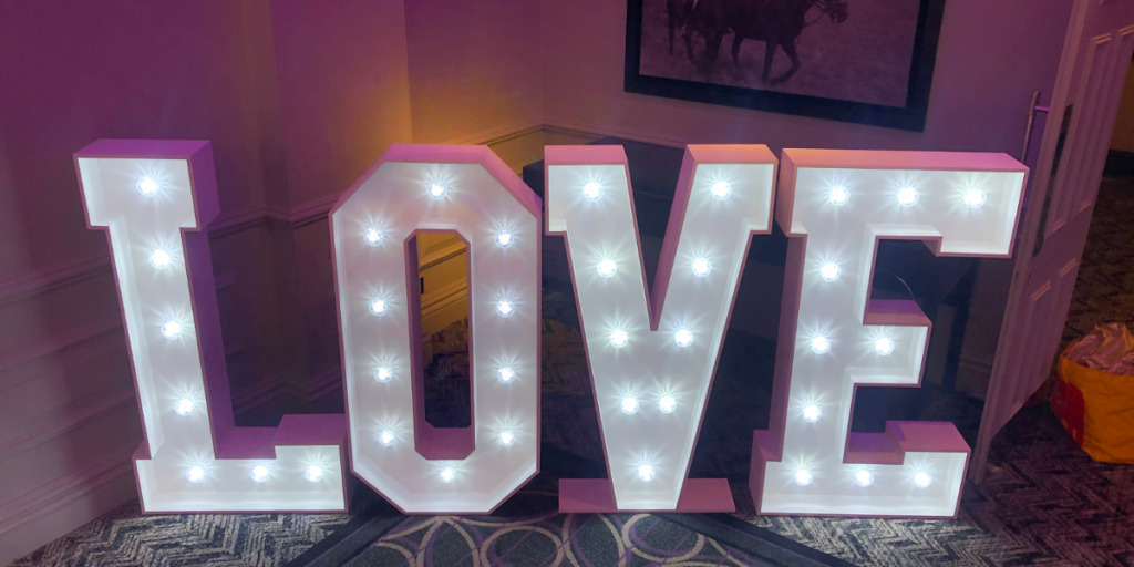 LOVE Letters – From £175 Our 4ft ‘LOVE’ letters are the essence of romance turned into a radiant spectacle. Each letter stands tall, casting a soft, inviting glow that harmonises with the joyful celebration of your union. These aren’t just letters; they are the beacons of your love story, meticulously designed with bright, energy-efficient LED bulbs that offer an enchanting luminescence to your venue. Whether nestled by the dance floor, welcoming guests at the entrance, or serving as an exquisite photo backdrop, our ‘LOVE’ letters are more than decor—they are a memorable experience. Their timeless design complements any wedding theme, from the ultra-modern to the whimsically vintage, transforming your space into a storybook setting. Mr & Mrs Letters – From £225 Celebrate the beginning of your forever with our ‘Mr & Mrs’ letters, a testament to your newly shared surname. These 4ft symbols of commitment and togetherness are not only an elegant decorative element but also a tribute to the journey you embark upon as life partners. Each character glows with the promise of future happiness, standing as a proud announcement of your marital bond. The letters’ soft lighting adds an air of sophistication to your reception, inviting guests to revel in the essence of your wedding day. Designed with versatility in mind, they adapt seamlessly to any setting, providing a focal point that is both visually stunning and deeply personal. These letters don’t just spell out a title; they encapsulate the essence of the wedding celebration—unity, love, and a touch of grandeur.